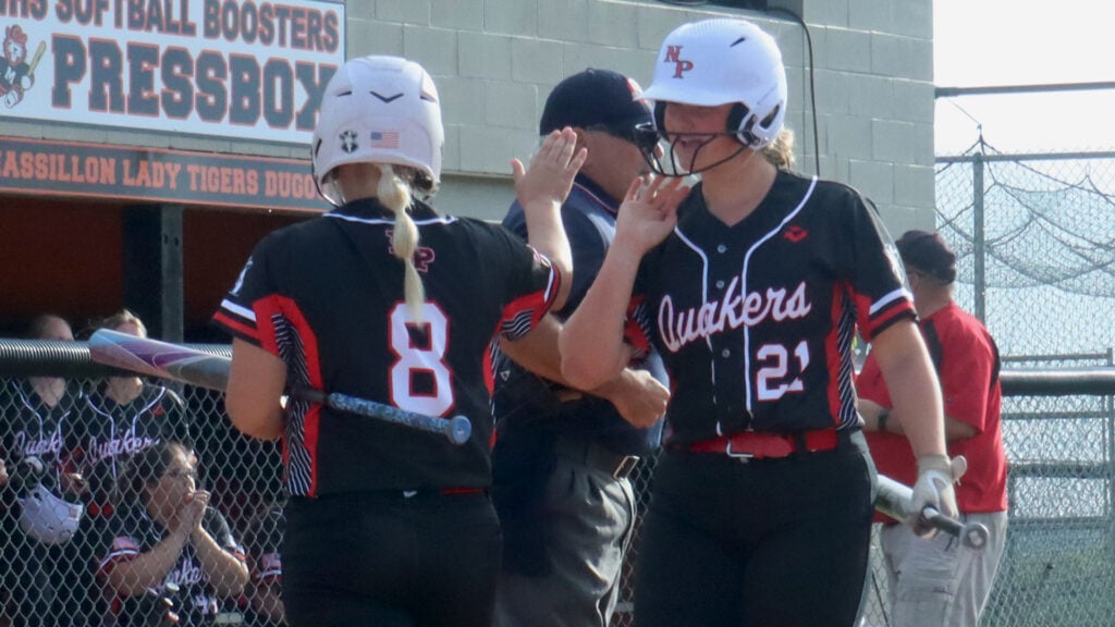 New Philadelphia's Ellie Mason (21) high-fives Madison Wright (8) after scoring a run during Tuesday's Division I District semifinal at Massillon High School.