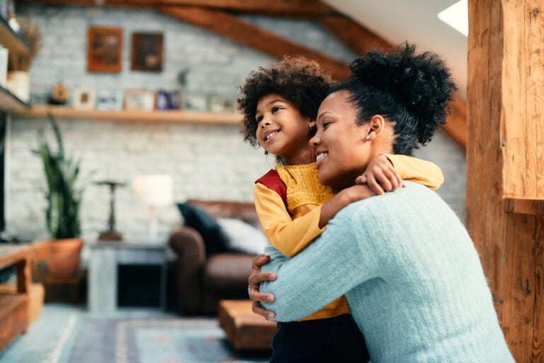 african american mother and daughter embracing on girl's first day of school.